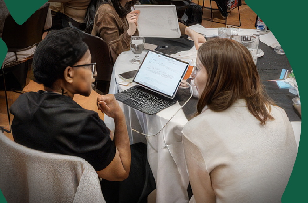 People who are sitting at a table, talking and working together on a laptop.