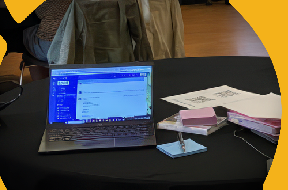 Open laptop and binders with printed materials on a table along with small sticky note pads.