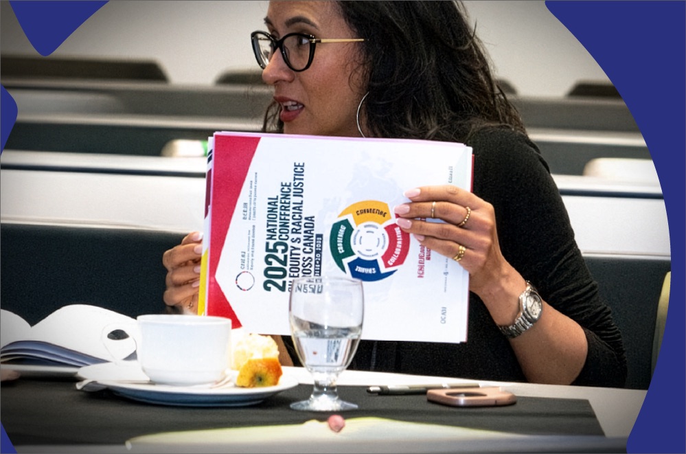 Two people sitting at a table discussing a printed document with the title "Equity & Racial Justice Across Canada.
